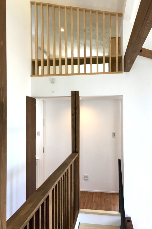 鉄骨階段と木製スリットが調和する開放的な吹き抜けの家。